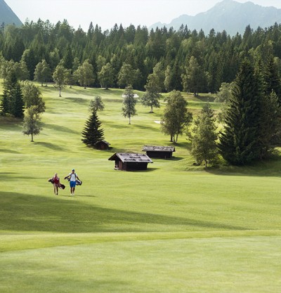 zwei Golfer auf dem Golfplatz mit Bergen im Hintergrund